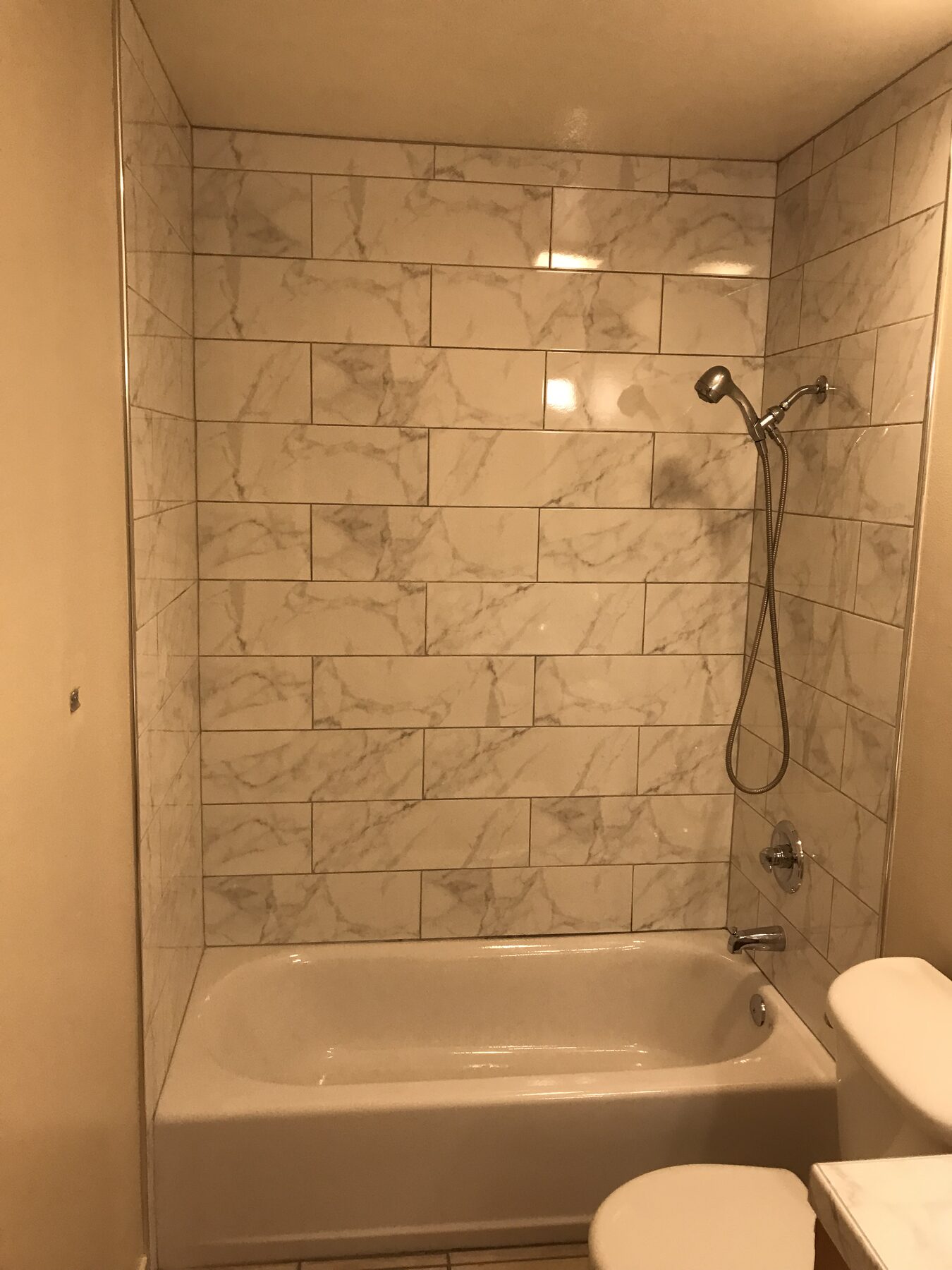 Tub and shower surround in marble-look porcelain tile in warm light